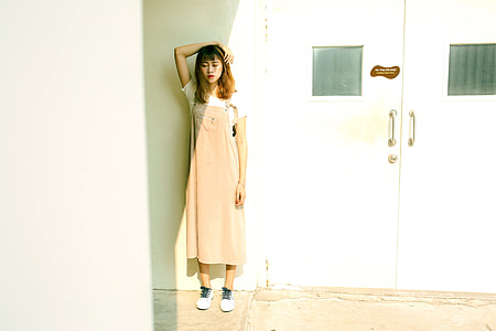 woman wearing beige jump skirt standing against white wall under the sunlight thumbnail