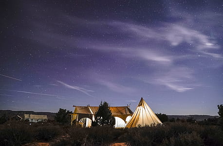 white tent beside canopy with side walls under blue cloudy skies at night time thumbnail