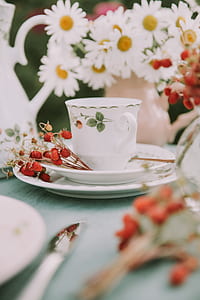 teacup on table with red and white flowers thumbnail