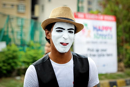 Selective Focus Photography of Man Wearing White Mask and Brown Fedora Hat thumbnail