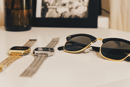 black clubmaster sunglasses and two digital watches on white table thumbnail