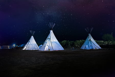 three white tipi outdoor tents at nighttime thumbnail