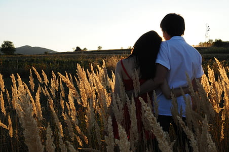 woman wearing red spaghetti strap top beside man wearing white dress shirt on green grass field photo thumbnail