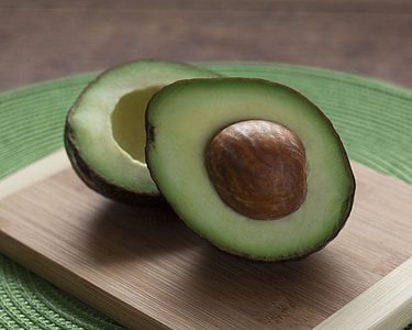 two sliced avocados on brown wooden chopping board thumbnail