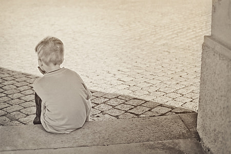 gray scale photography of boy sitting on concrete floor thumbnail