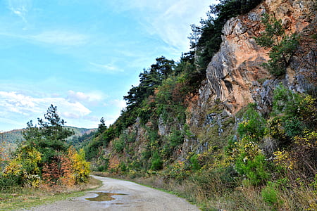 panoramic photo of rock formation beside dirt road thumbnail