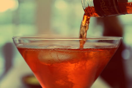 clear cocktail glass with brown liquid in tilt shift photography thumbnail