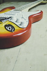 red and yellow electric guitar on white surface thumbnail