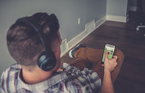 man wearing black Bluetooth headset and holding white Android smartphone thumbnail