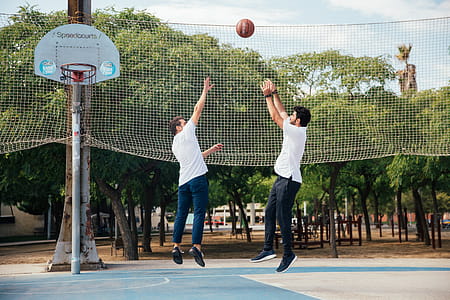 Two young men playing basketball in the day time thumbnail