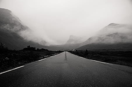 grayscale photo of road with overlooking view of mountains and fog thumbnail