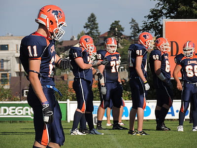 football players standing on green grass field during daytime thumbnail