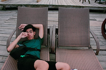 Man Wearing Green Shirt and Black Shorts Laying on Lounger thumbnail
