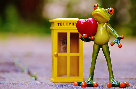 miniature photography of frog figurine beside telephone booth thumbnail