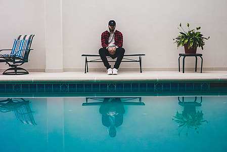 man sitting on bench in front of pool at daytime thumbnail