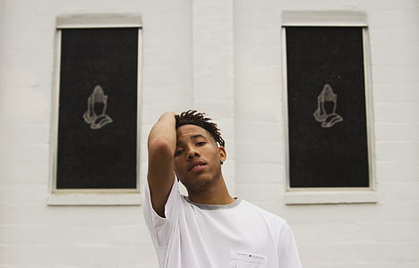 man holding his head standing in front wall thumbnail
