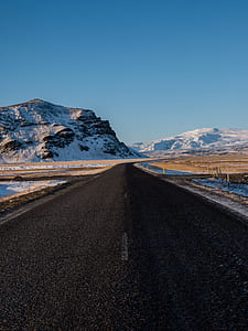 road way beside body of water and mountain during day time thumbnail