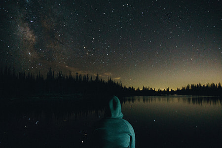 person sitting in front of body of water under night sky thumbnail