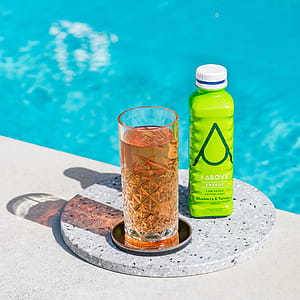 clear drinking glass beside bottle near swimming pool thumbnail