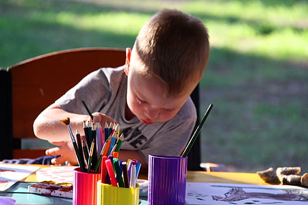boy wearing grey shirt drawing on table with assorted color pencil thumbnail