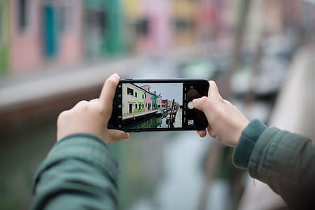 focus photography of person taking photo the river on smartphone thumbnail