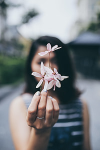 focus photo of pink-petaled flowers held by a woman in grey and black horizontal stripe sheath dress thumbnail
