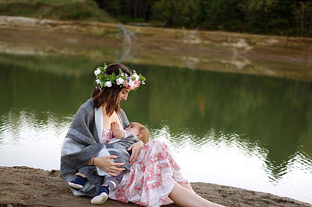 woman wearing white and pink floral top while carrying her baby thumbnail