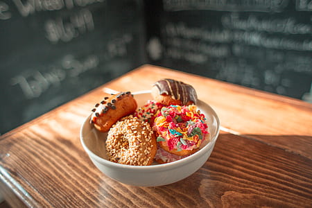 doughnuts in white ceramic bowl on brown wooden surface thumbnail
