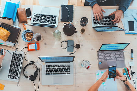 gray laptop computers and assorted-type gadgets and items on brown wooden table thumbnail