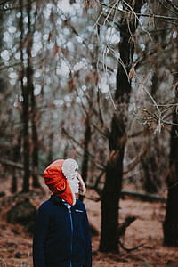 boy wearing red aviator cap and black jacket standing in the wood thumbnail