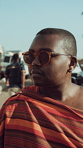 man wearing orange and grey thobe and sunglasses during daytime thumbnail