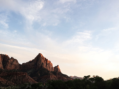 low-angle photography of rock formation near green trees thumbnail