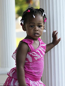 toddler girl standing beside post during day thumbnail