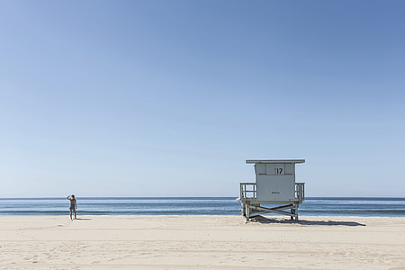 person standing on seashore near cottage thumbnail