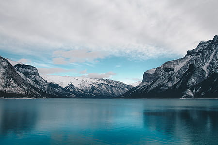 body of water near high-rise mountain under blue and cloudy sky thumbnail