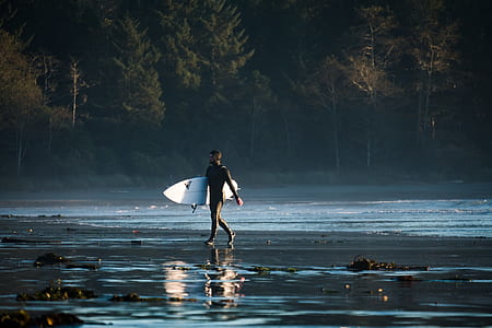 man carrying white surfboard on seaside thumbnail