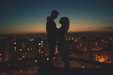 silhouette of man and woman standing on top of building thumbnail