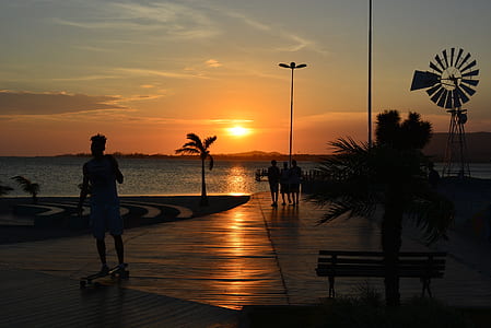 silhouette photography of people standing on dock during sunset thumbnail