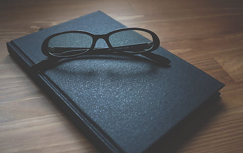 black framed eyeglasses with hardbound book thumbnail
