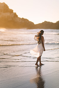 silhouette photography of woman standing near the body of water thumbnail