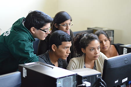 five people sitting and standing in front of computer thumbnail