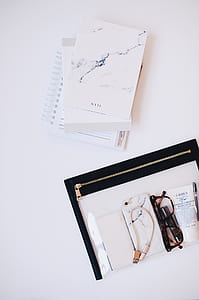three books next to black pouch with smartphones and eyeglasses thumbnail