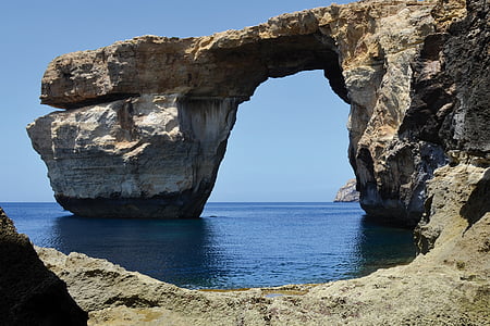 brown arch rock near body of water during daytime thumbnail