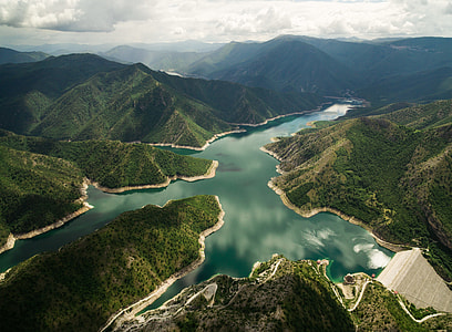 aerial photography of body of water surrounded by green mountains thumbnail