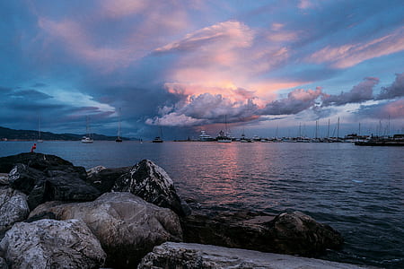group of boats on body of water under gray and white clouds thumbnail