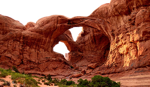 green leaf trees growing beside rock formation with hole in the middle under clear sky panoramic photography thumbnail