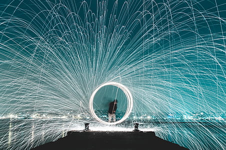 steel wool photography of man on wooden dock between body of water thumbnail