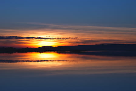 body of water and mountains during sunset thumbnail