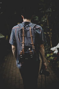 man walking while carrying camera towards pathway thumbnail