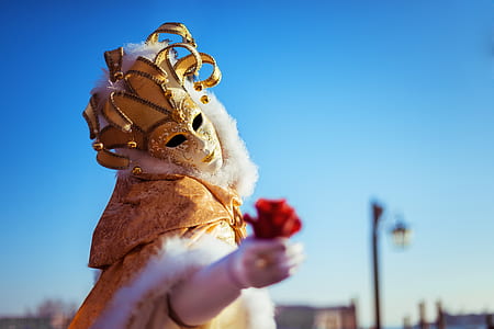 selective focus photography of person wearing white and gold mask thumbnail